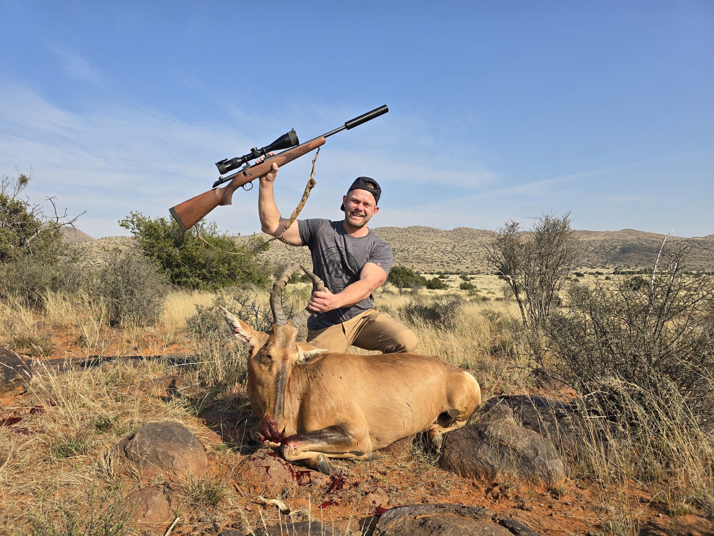 Hunter celebrating a red hartebeest with rifle raised in the Karoo