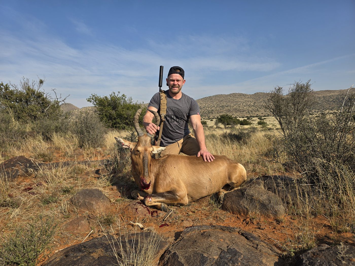 Hunter with a red hartebeest in the open Karoo veld